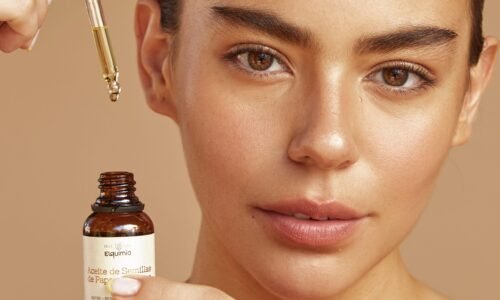 Botella de Aceite de Semillas de Papaya Elquimia estilo catálogo premium sobre fondo cálido